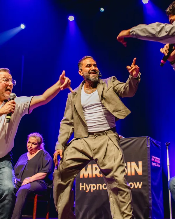 Mr.Yasin tanzt lachend mit Teilnehmern auf der Bühne der HypnoX Show